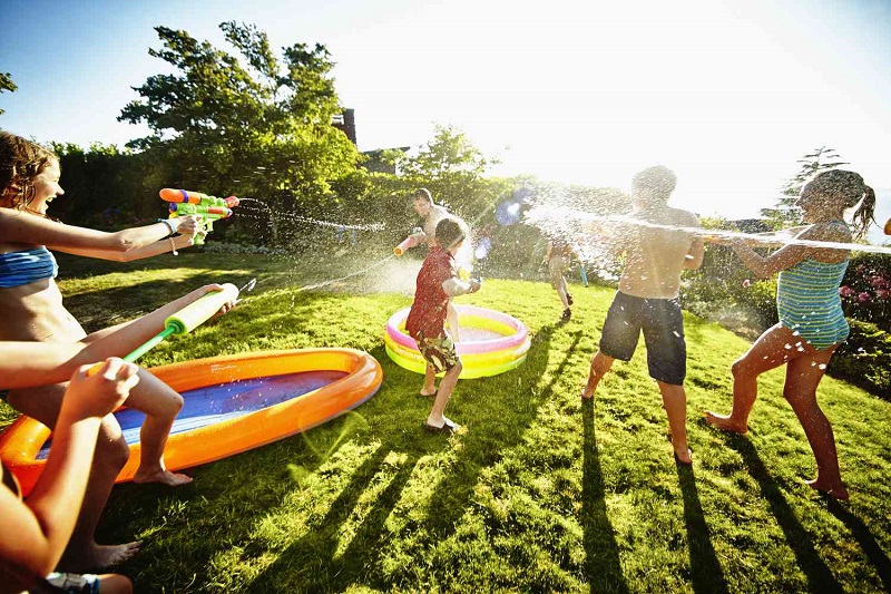 children playing with water guns in a backyard with swimsuits on