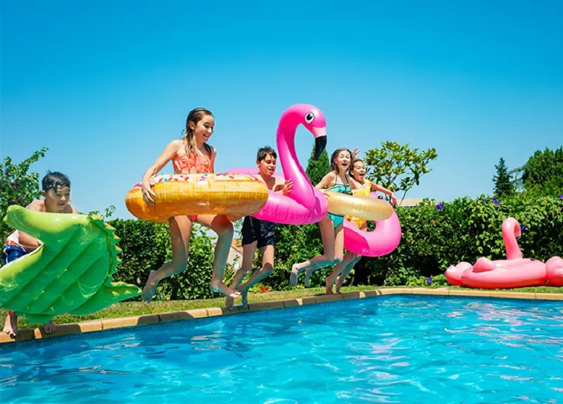 kids jumping in a backyard pool with their inflatabl
