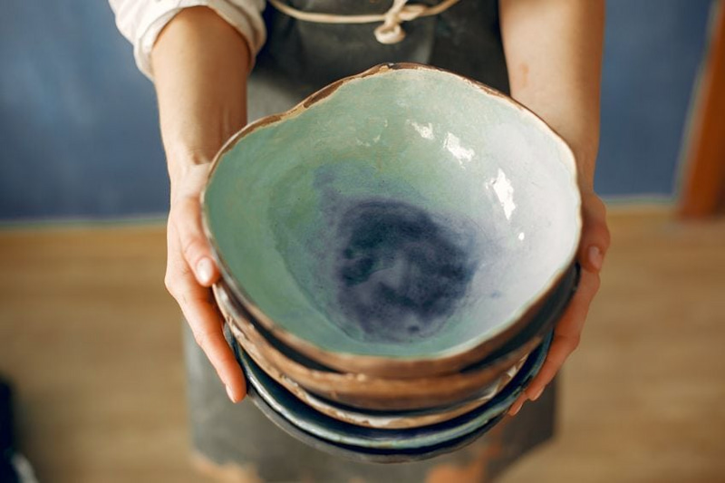 person holding ceramic bowls painted with acrylic paint